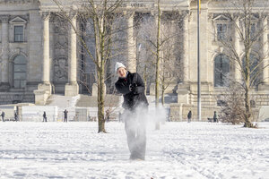 Eine Frau spielt im Schnee vor dem Reichstagsgebäude Golf