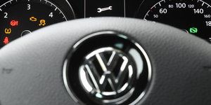 Ein VW-Symbol, im Hintergrund ein Schraubenschlüssel in einem Display
