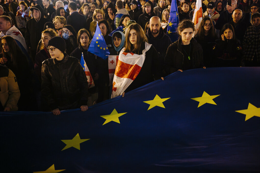 Menschen stehen zusammen und halten eine übergroße europäische Fahne