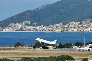 Ein Flugzeug startet, im Hintergrund ist ein Strand und Meer zu sehen