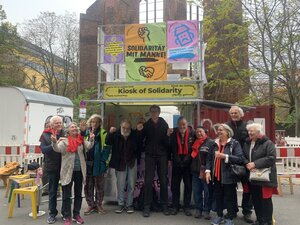 Manfred Moslehenr und seine Unterstützer:innen am Dienstag vor dem Berliner Landgericht. Sie stehen vor dem Kiosk der Solidarität und recken die Fäuste in die Luft