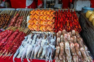 Geröstete und rohe Insekten, Seidenraupen, Skorpione, Käfer, Garnelen, Krabben, Langusten, Schlangen, Hundefleisch, am Stiel an einem Marktstand