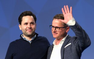 Johannes Winkel und Carsten Linnemann stehen nebeneinander. Linnemann winkt mit seiner linken Hand