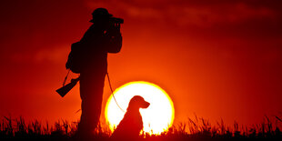 Jäger mit Hund und Fernglas