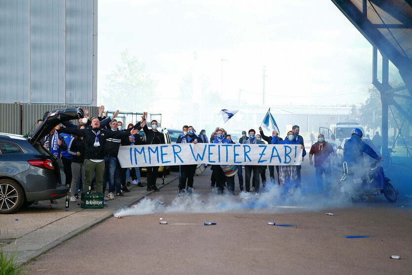 Die Handball-Fans aus Dessau stehen mit einem Banner und Pyrotechnik vor der Halle.