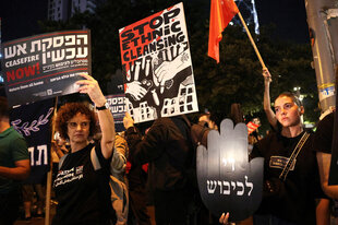 Demonstrierende Israelis in Tel Aviv mit Plakaten auf Hebräisch und Englisch: "Stop ethnic cleansing"