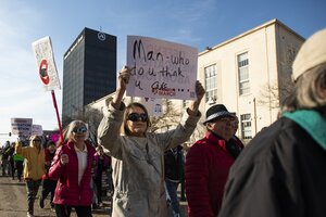 Menschen protestieren, einige halten Schilder in die Höhe, auf einem steht: 