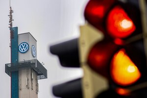 Eine rote Ampel leuchtet vor dem großen VW-Logo am Werk in Osnabrück.