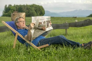 Ein Mann liegt im Liegestuhl und liest die Süddeutsche Zeitung