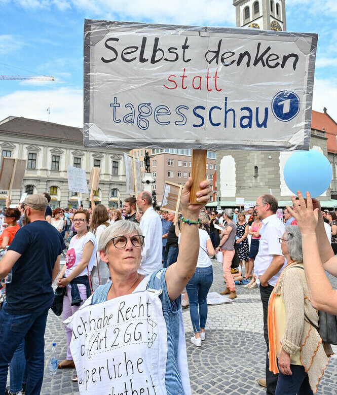 Eine Frau hält ein Plakat, daruf ist zu lesen: "Selber denken statt tagesschau"