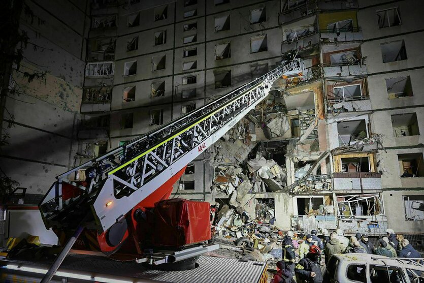 Ein Wohnhaus mit beschädigter Hauswand, davor ein Kran und Rettungskräfte