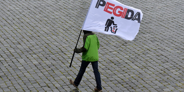 Eine Person mit Pegida-Fahne