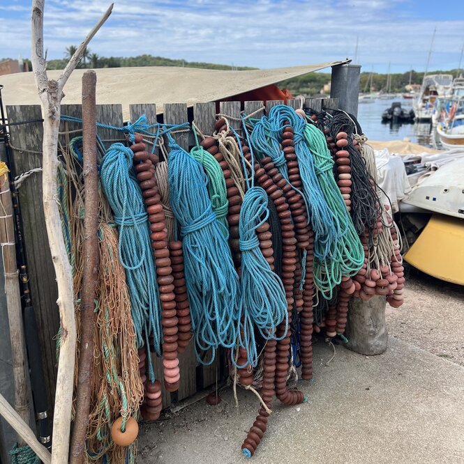 Blaue Fischerleinen hängen zum Trocknen auf an einem Zaun im Hafen von Porquerolles