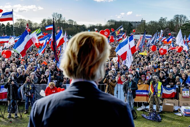 Der Rechtspopulist Geert Wilders steht vor einer Menschenmenge. Viele schwenken niederländische Fahnen