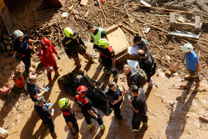 Luftaufnahme mehrerer Menschen und Hilfskräfte, die in vom Hochwasser erschaffenen Trümmern stehen