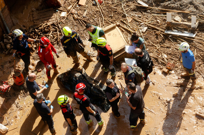 Luftaufnahme mehrerer Menschen und Hilfskräfte, die in vom Hochwasser erschaffenen Trümmern stehen