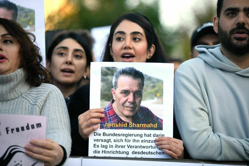 Menschen protestieren mit Bildern von Jamshid Sharmahd vor dem iranischen Konsulat in Frankfurt am Main