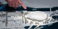 Finger zeigt auf ein weißes Modell des Olympiastadions von Hamburg