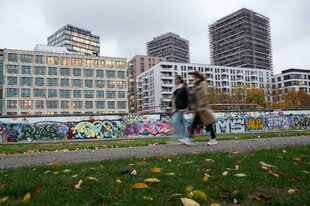 Menschen laufen an der East-Side-Gallery entlang