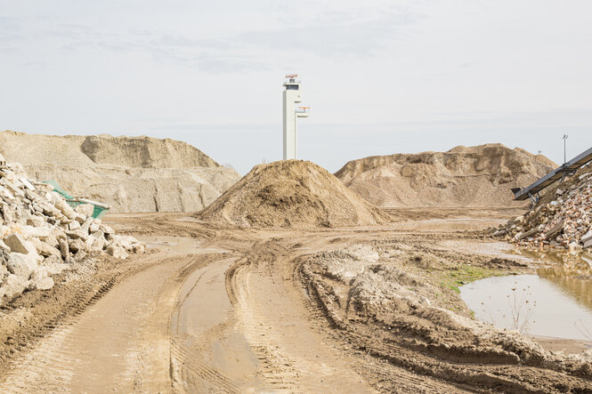 Eine wüstenähnliche Landschaft mit Türmen des Flughafens im Hintergrund