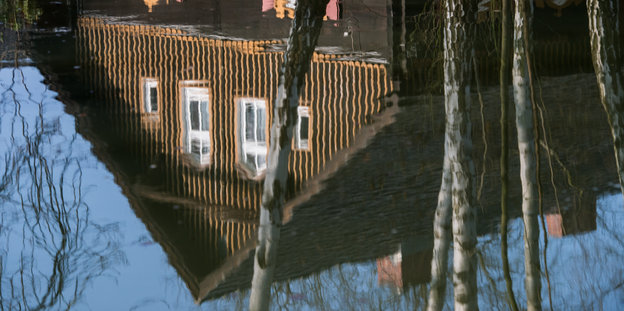 Ein Haus in Brandenburg spiegelt sich in einer Pfütze.