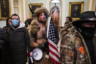 Trump-Unterstützer im Kapitol, darunter einer mit freiem Oberkörper, USA-Flagge und Hörnern auf dem Kopf