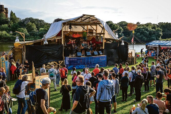 Eine Band spielt auf einer Open-Air-Bühne auf dem Festival Breminale. Davor stehen Menschen und hören zu.