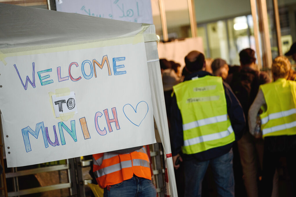 Freiwillige Helfer stehen am 5.9.2015 am Hauptbahnhof in München neben einem Schild mit der Aufschrift "Welcome to Munich".