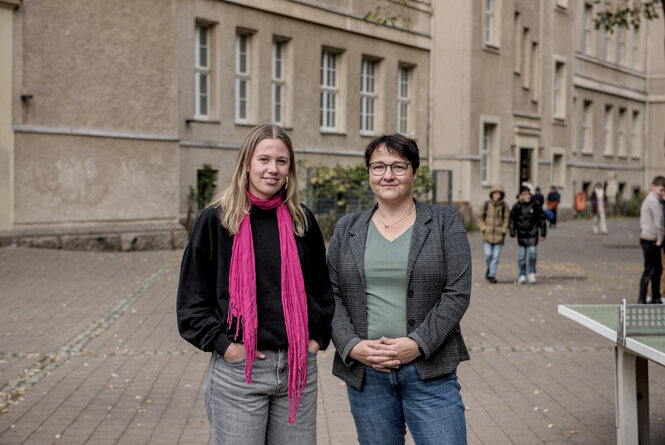 Zwei Personen auf einem Schulhof.