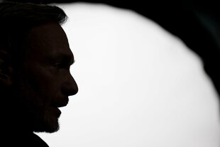 Lindner im Profil. Das Profil ist komplett schwarz, dahinter ein heller Lichtkegel, umgeben von Schatten, wie bei einem Scherenschnitt.