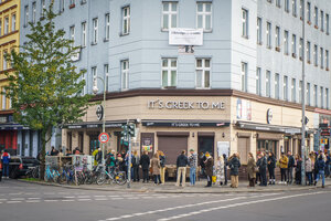 Eine wartende Menschenschlange auf dem Gehweg vor Wohnhäusern