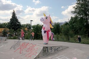 Eine Frau steht in einem Einhornkostüm auf einer Skaterbahn