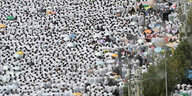 Hunderte Menschen pilgern in weißen Gewändern