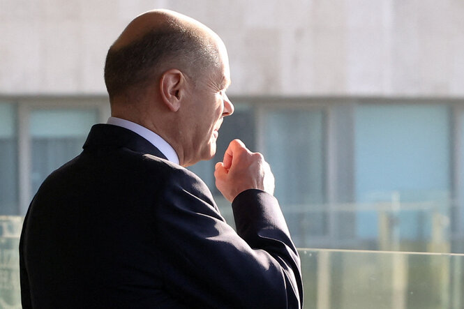 Kanzler Olaf Scholz steht an einem Fenster.