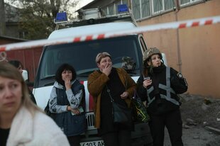 Mehrere Menschen stehen schockiert an einer Straßensperre.