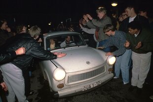 Ein Trabbi wird von vielen Menschen begrüßt.