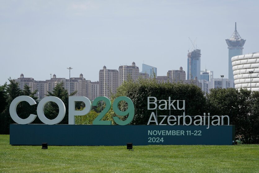 Schriftzug "COP 29 Baku Azerbaijan" vor Stadtkulisse.