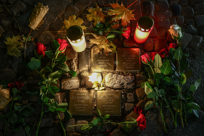 Kerzen und Rosen an Stolpersteinen.