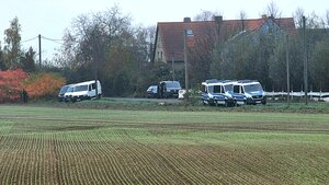 Neblige Herbst-Stimmung auf dem Land, Polizeiautos stehen am Rande eines Ackers, im Hintergrund ist ein Haus mit Zaun umgeben von Bäumen zu sehen