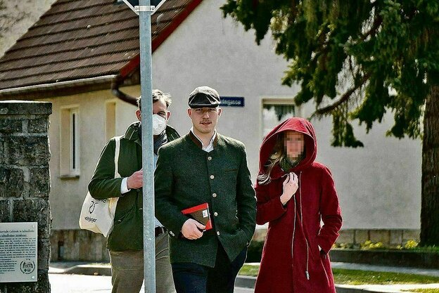 Kurt Hättasch in Trachtenjacke und Kappi unterwegs mit seiner Frau, die einen roten Mantel mit großer Kapuze trägt