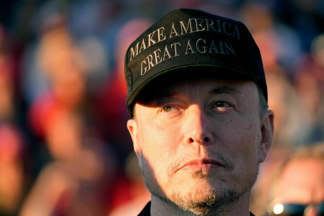 Elon Musk guckt tragisch und trägt ein Baseball-Cap mit der Aufschrift: Make America Great Again