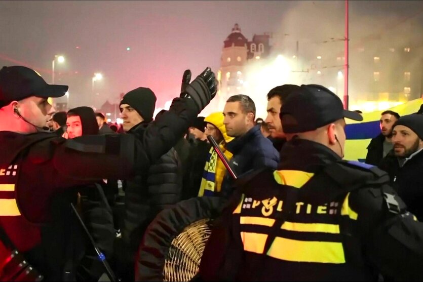 Polizisten mit gelben Warnwesten stehen Spalier für Maccabi Tel-Aviv Fans