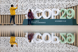 Menschen stehen vor dem Schriftzug "COP29" in Baku