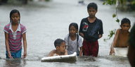 Kinder stehen Hüfttief im Wasser auf der Straße.
