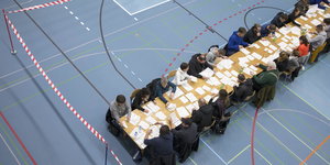 Wahlhelfer sitzen an beiden Seiten eines langen Tisches