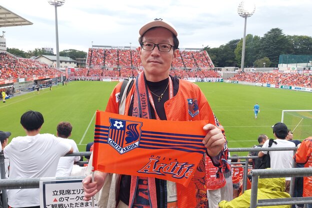 Ein Mann in orangener Fan-Montur auf der Stadion-Tribüne