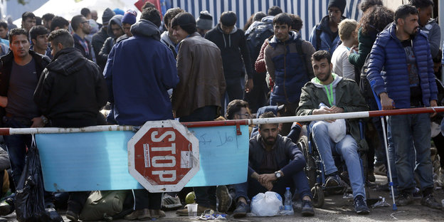 Flüchtlinge stehen, sitzen und warten
