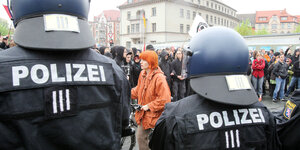 Polizisten mit Helm stehen mit derm Rücken zur Kamera und sperren eine Demonstration ab