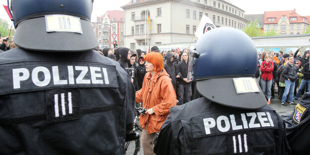 Polizisten mit Helm stehen mit derm Rücken zur Kamera und sperren eine Demonstration ab