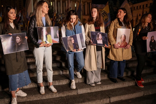 Mehrere Personen protestieren und halten Schilder mit einem Porträt hoch.